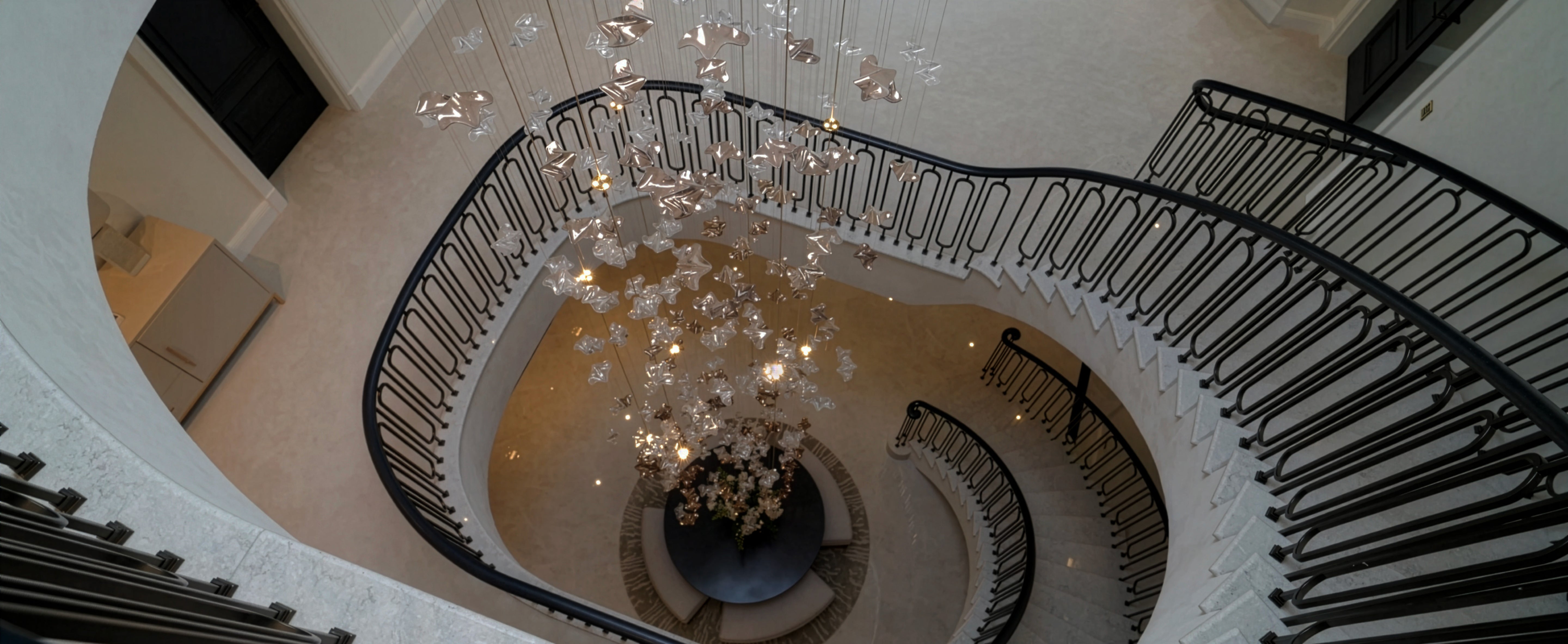 Elegant spiral staircase with modern chandelier and luxury lighting design