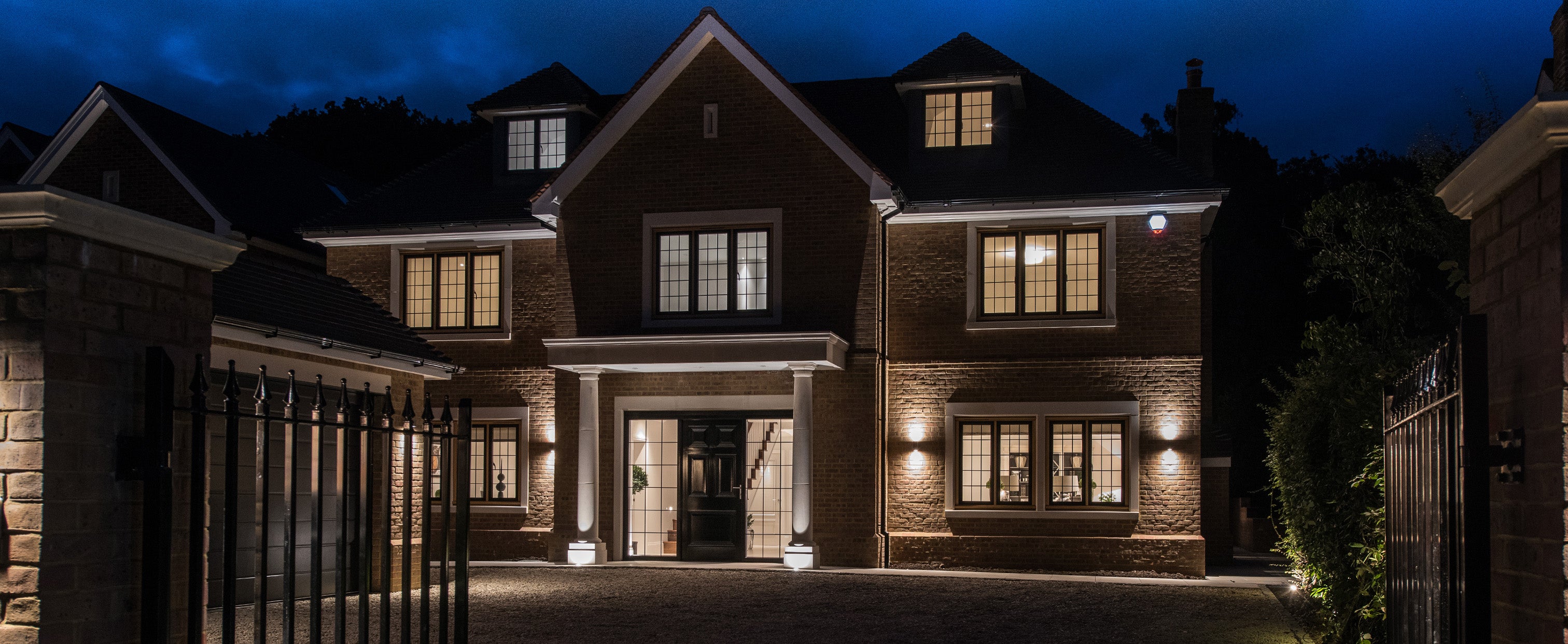 Luxury home exterior lighting design at night, showcasing integrated architectural illumination for residential properties