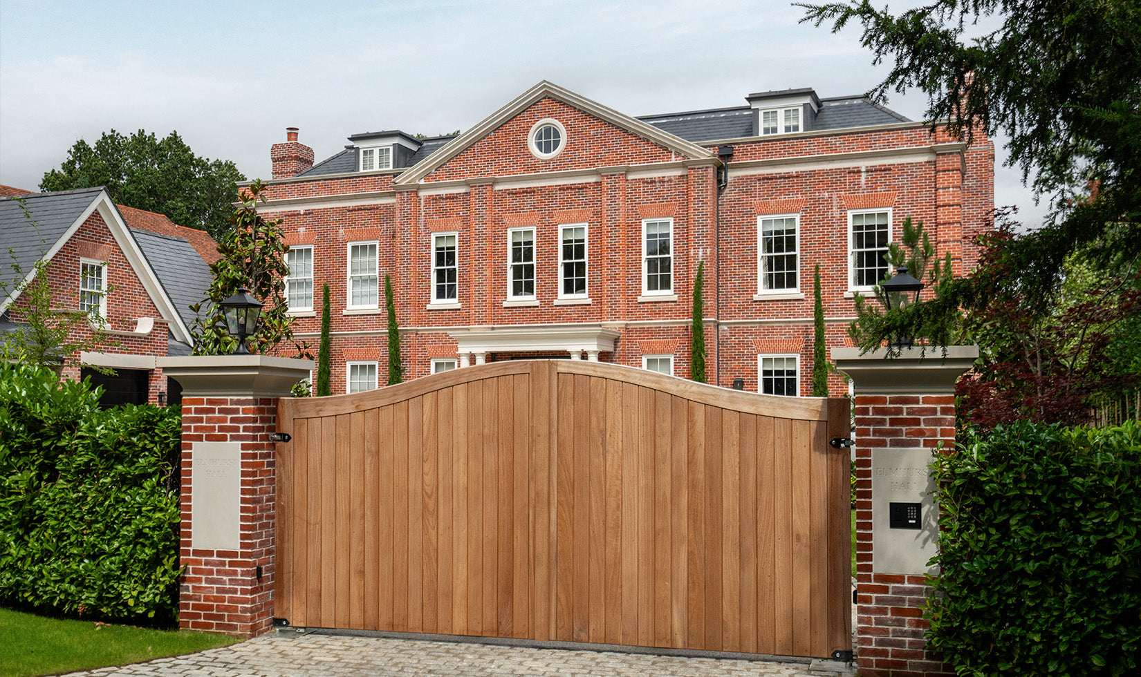 Luxury brick mansion with wooden gate, ideal for residential AV and lighting design projects