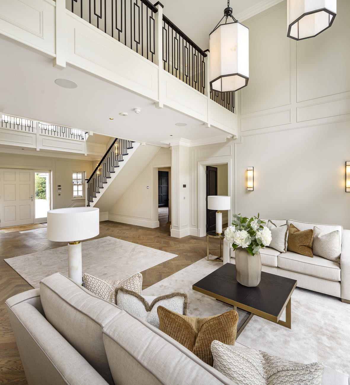 Luxury living room with modern lighting, elegant staircase, and integrated AV design