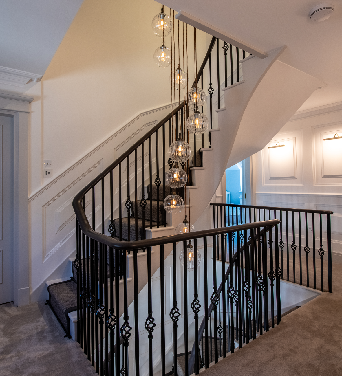 Elegant staircase with black iron railings and modern pendant lighting for luxury home design