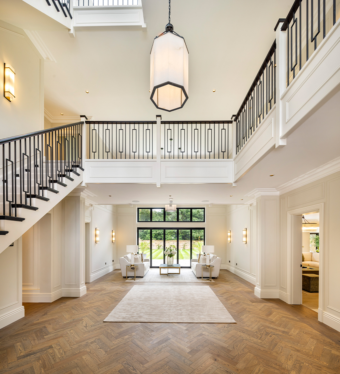 Luxury home interior with herringbone wood floors, modern lighting, and elegant staircase design