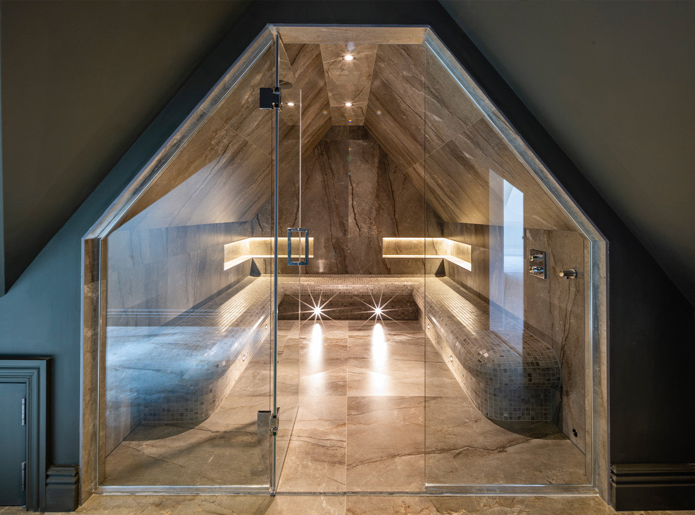 Luxury sauna with glass enclosure, marble walls, and integrated lighting design for residential wellness spaces
