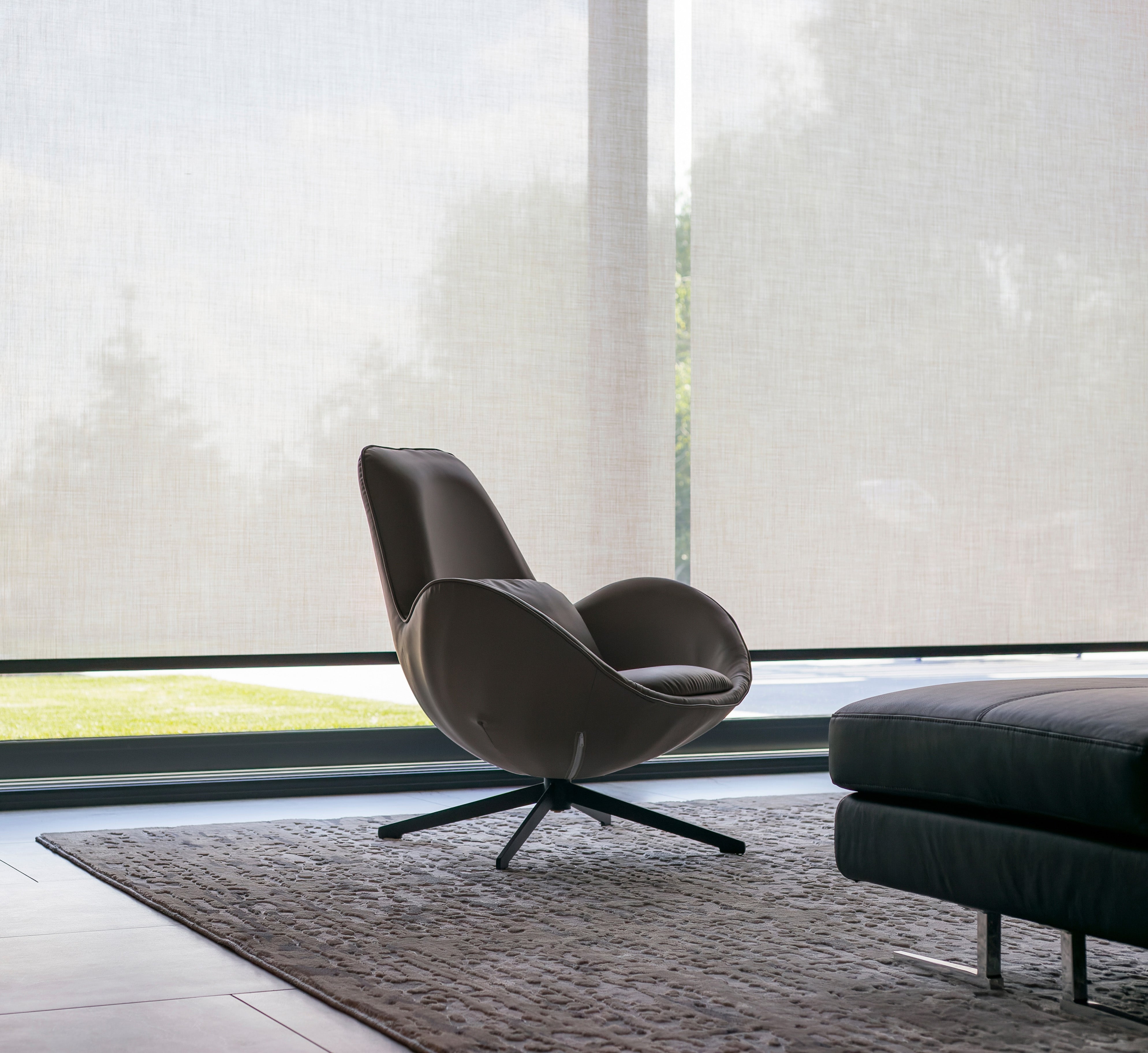 Modern leather lounge chair with swivel base in minimalist living room, ideal for residential lighting design projects